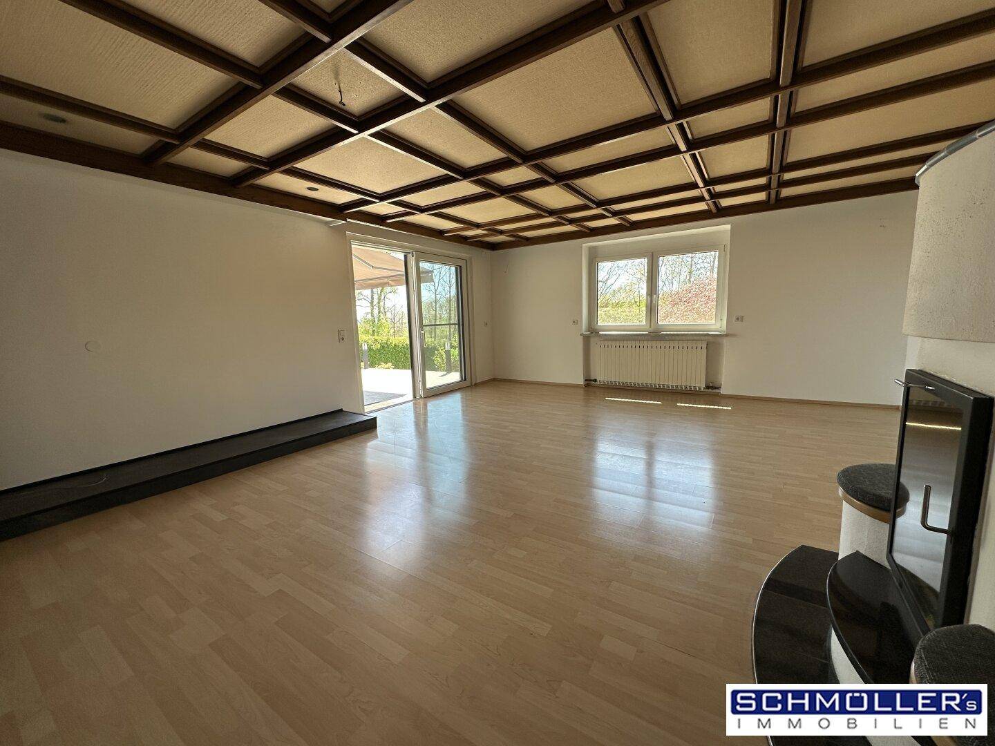 Geräumiges Wohnzimmer mit Holzbalkendecke, Parkettboden und Zugang zur sonnigen Terrasse.