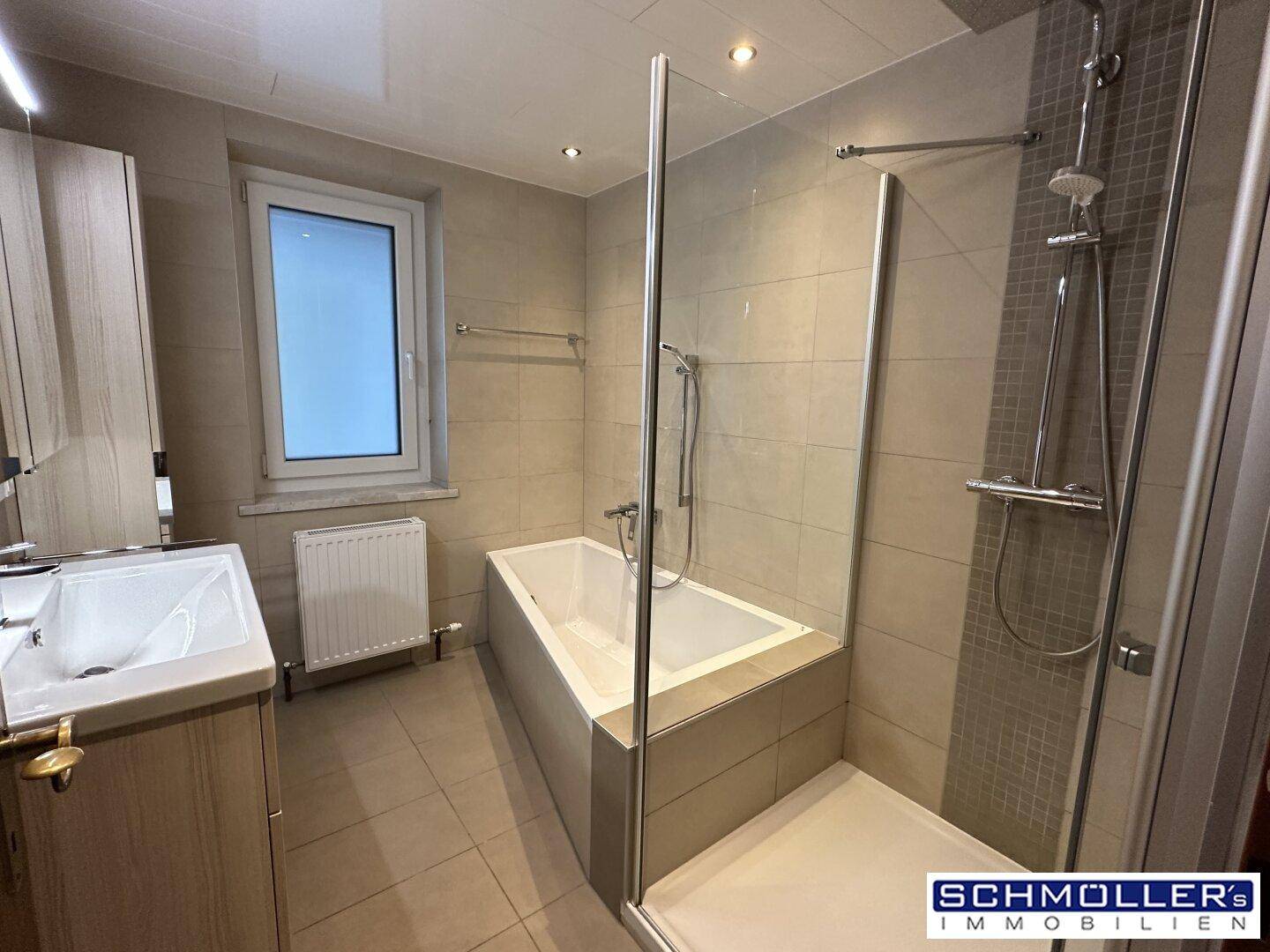 Geräumiges Badezimmer mit Badewanne, Duschbereich und modernem Waschtisch, hell gefliest.