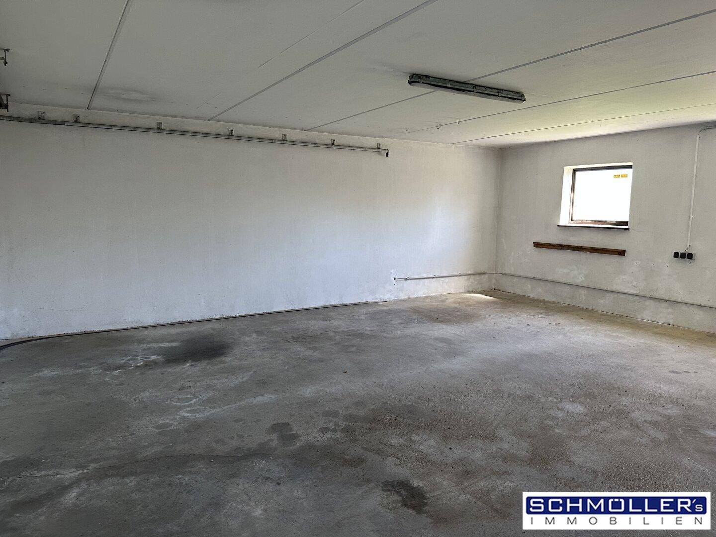 Geräumige Garage oder Lagerraum mit Betonboden und einem kleinen Fenster für Belüftung.