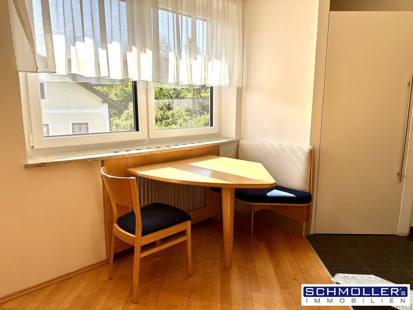 Gemütlicher Essbereich in der Küche mit Eckbank, Tisch und Blick ins Grüne durch das Fenster.