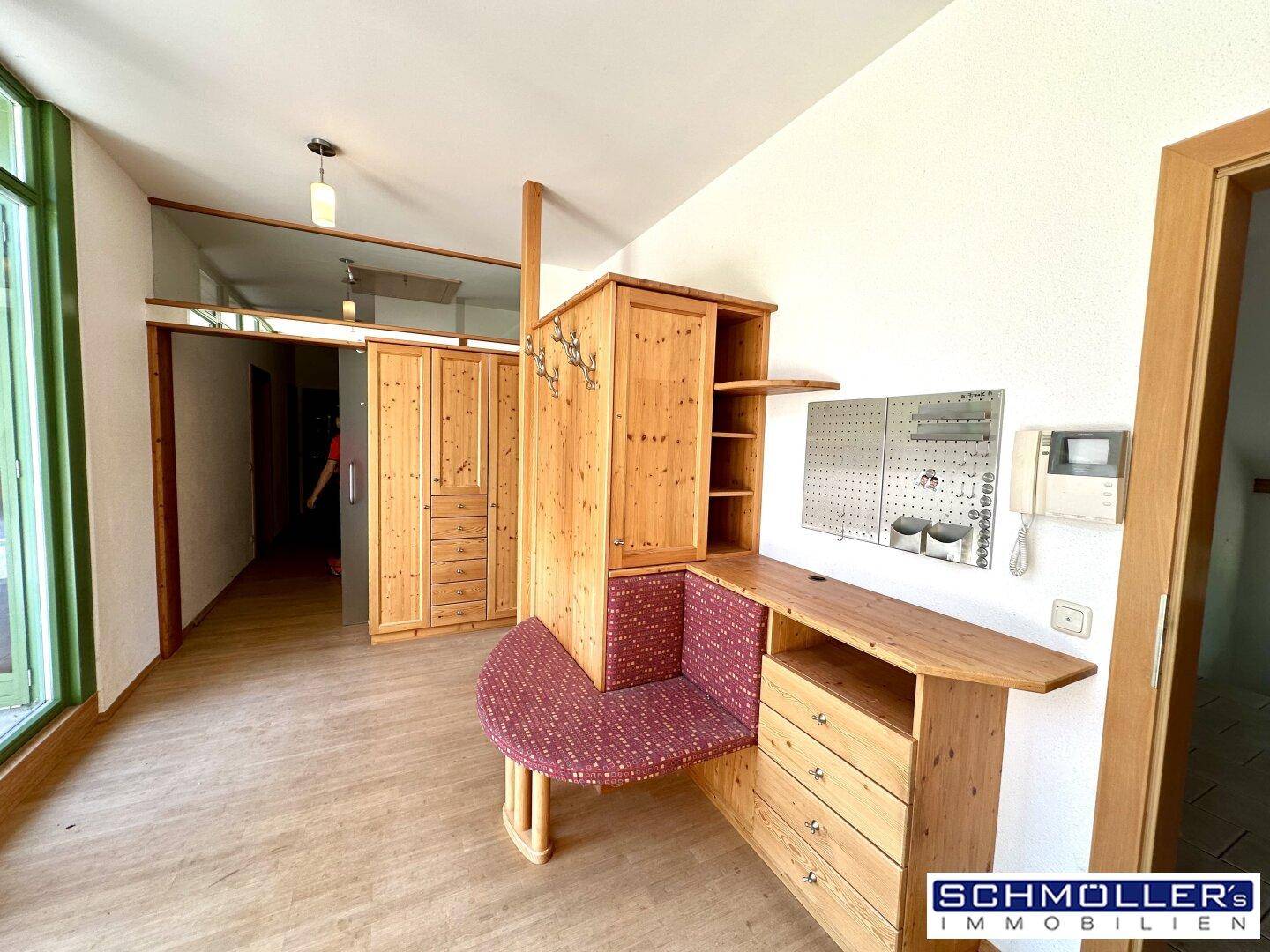 Heller Flur mit Einbauschränken aus hellem Holz und einem integrierten Sitzbereich.