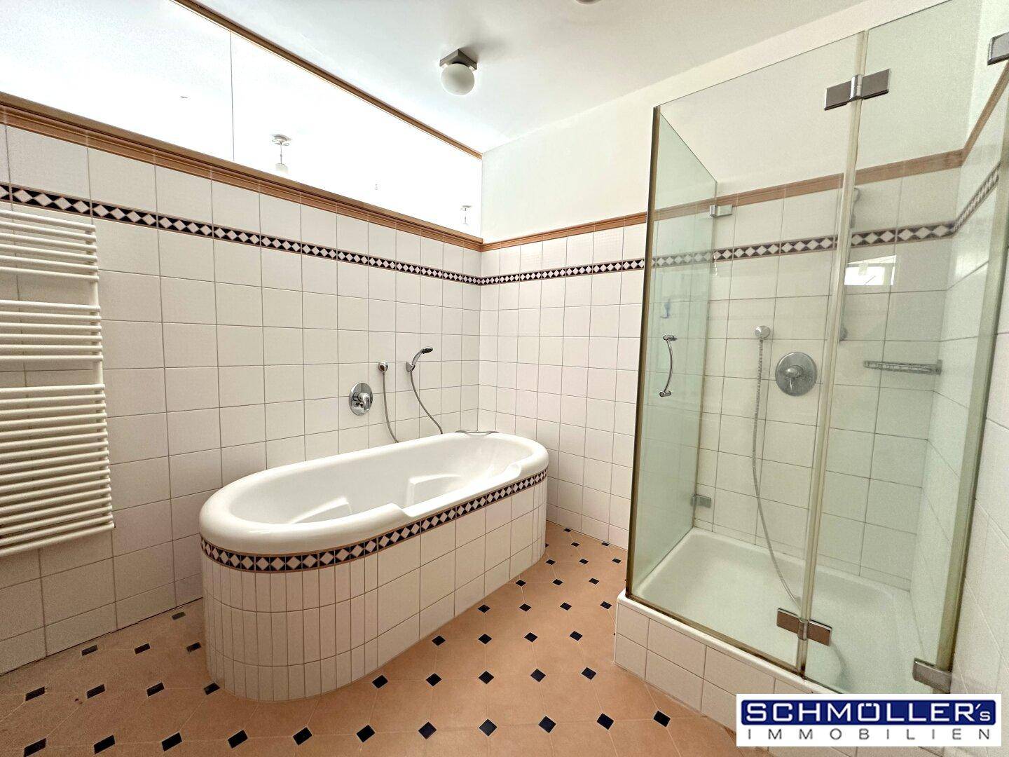 Geräumiges Badezimmer mit ovaler Badewanne, Duschkabine und beheiztem Handtuchhalter.