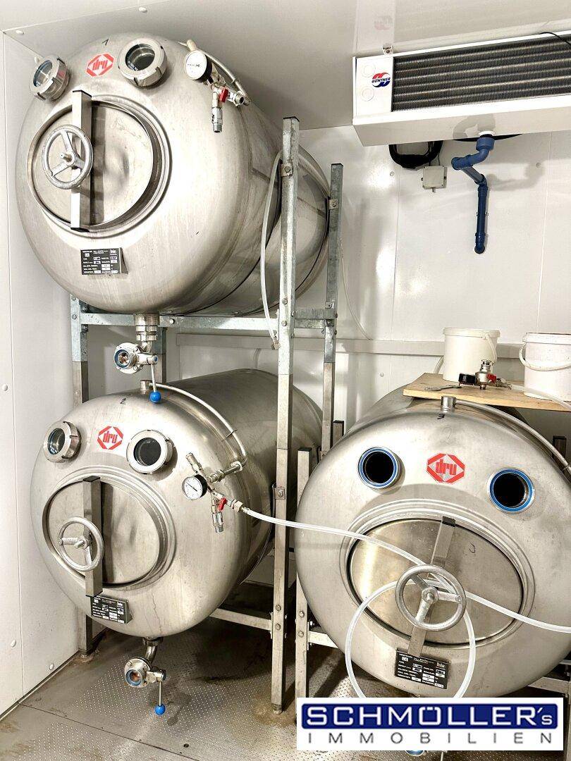 Detailansicht von mehreren großen Edelstahltanks mit Messgeräten in einem Produktionsbereich.