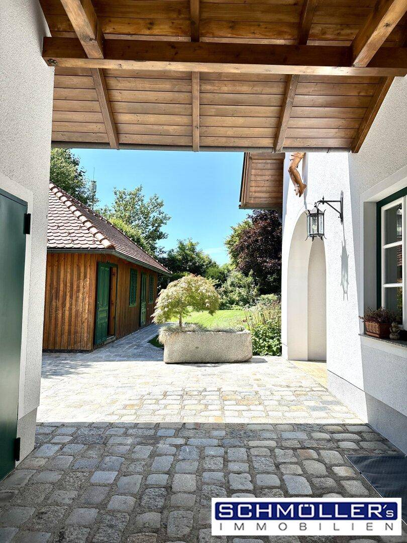 Überdachter Durchgang mit Kopfsteinpflaster und Blick auf ein charmantes Holzgebäude.
