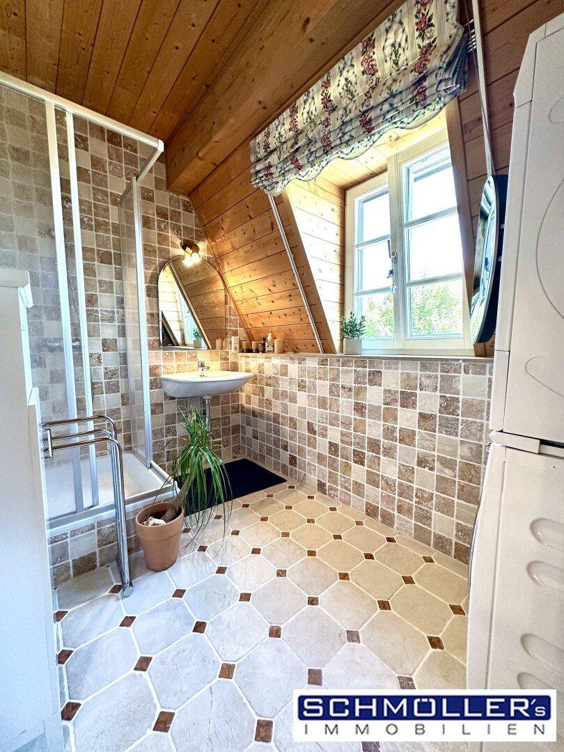Badezimmer im Dachgeschoss mit Dusche, gemusterten Fliesen und Fenster.