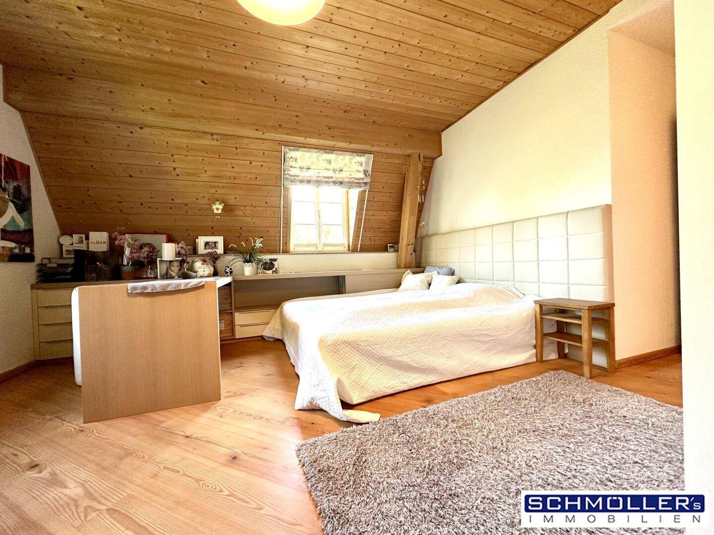 Gemütliches Schlafzimmer im Dachgeschoss mit Holzdecke und Holzboden.