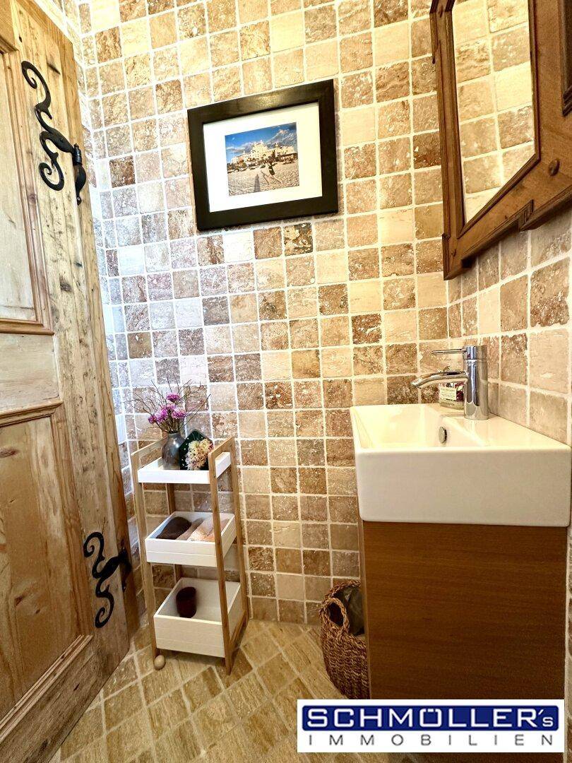 Kleines Gäste-WC mit gemusterten Fliesen, Holzdetails und modernem Waschbecken.
