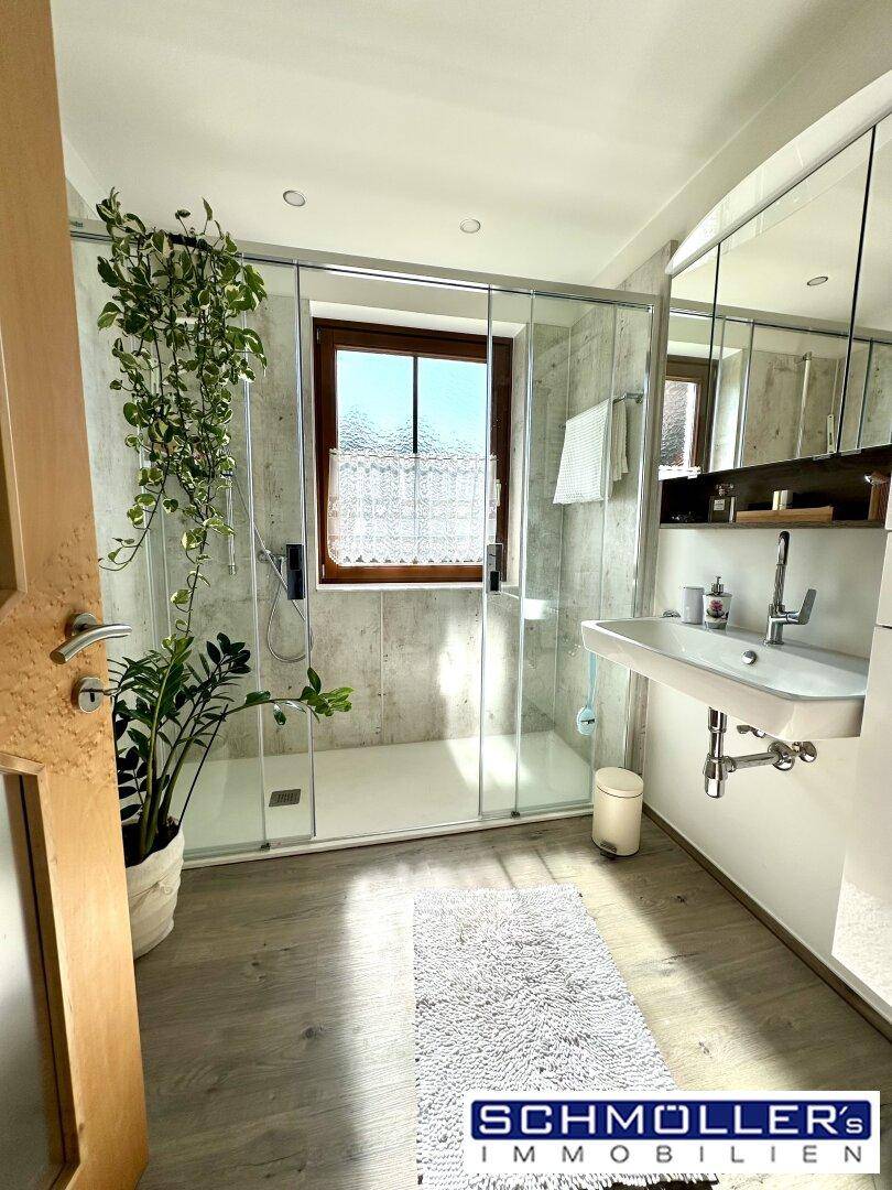 Modernes Badezimmer mit begehbarer Dusche, Waschbecken und einem Fenster für Tageslicht.