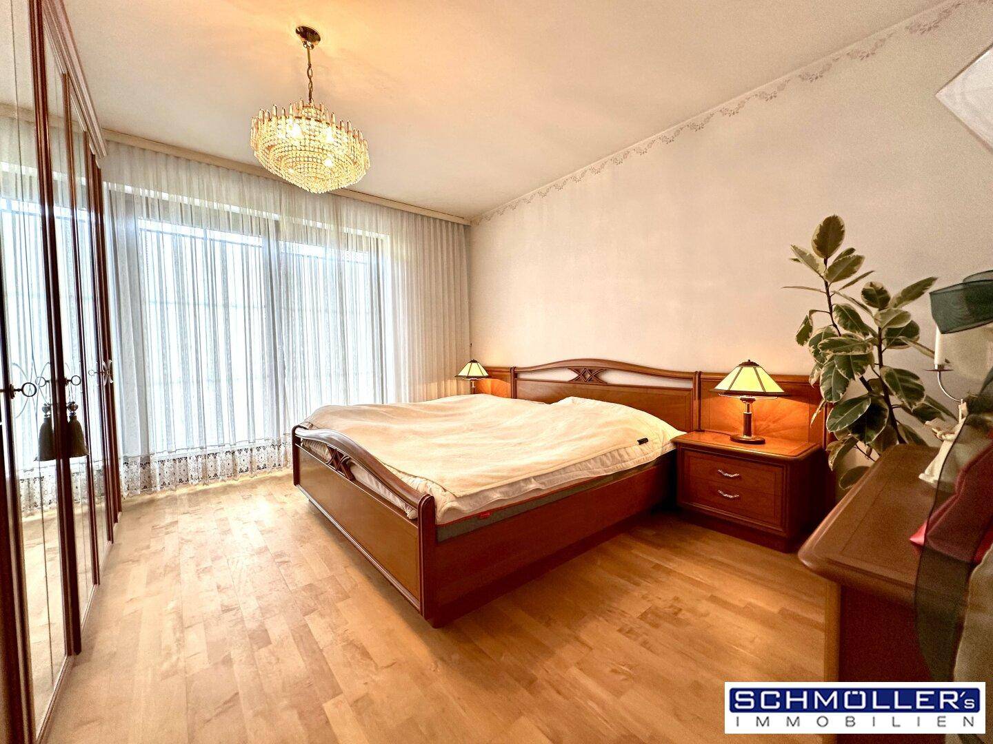Gemütliches Schlafzimmer mit Doppelbett, Holzmöbeln und einem großen Fenster mit Vorhängen.