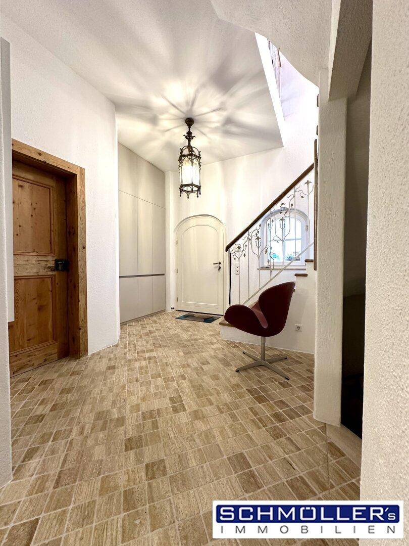 Heller Eingangsbereich mit gemustertem Fliesenboden, Holztreppe und moderner Beleuchtung.