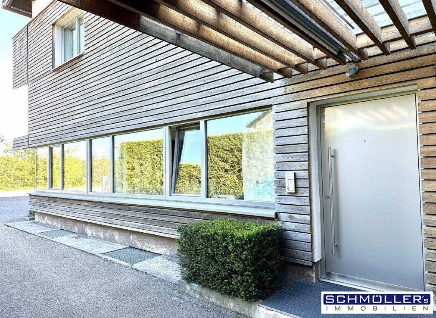Moderner Eingangsbereich mit Holzverkleidung und einer eleganten, undurchsichtigen Haustür.