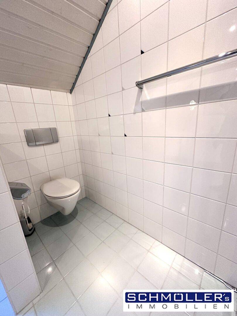 Separate Toilette mit Wand-WC und hellen Fliesen, passend zum Badezimmerstil.