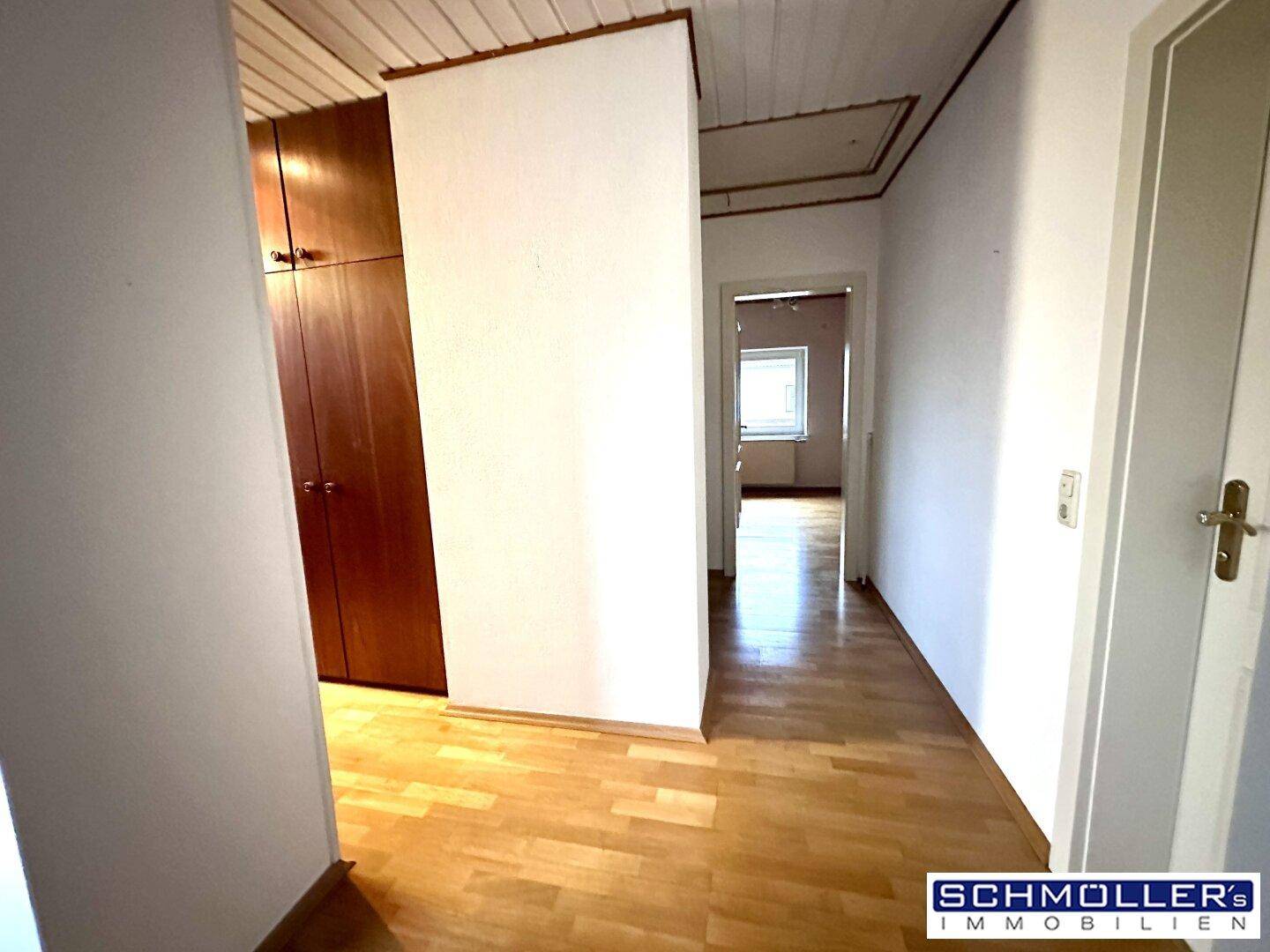 Obergeschossflur mit Holzparkettboden und Einbauschränken, der zu weiteren Zimmern führt.