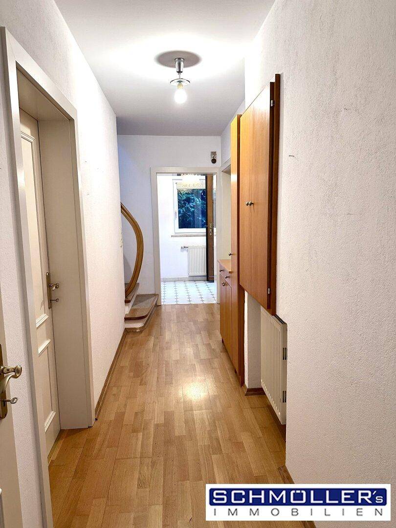Langer Flur mit Holzparkettboden, Einbauschränken und Blick in weitere Räume.