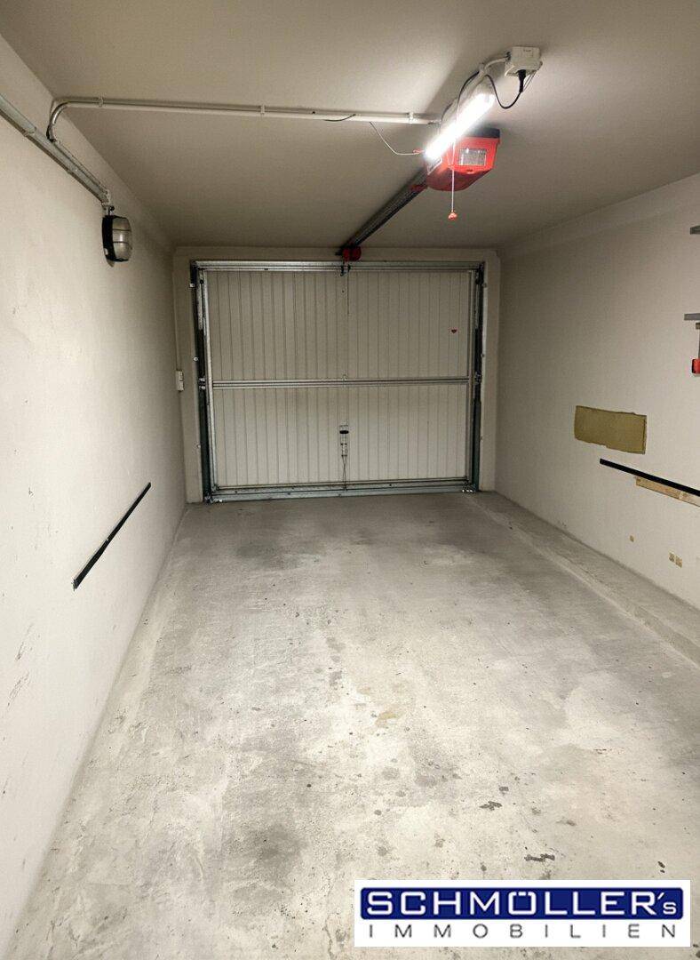 Innenansicht der Garage mit Betonboden und einem Rolltor, bereit für ein Fahrzeug.