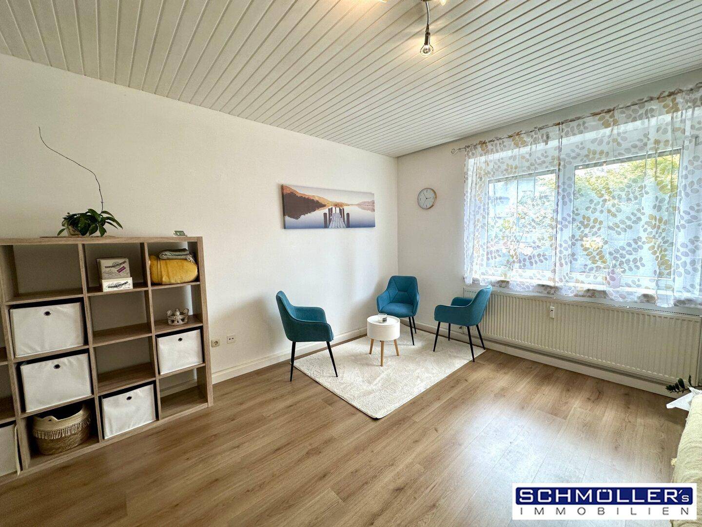 Helles Wohnzimmer mit Laminatboden, großem Fenster und moderner Dekoration.