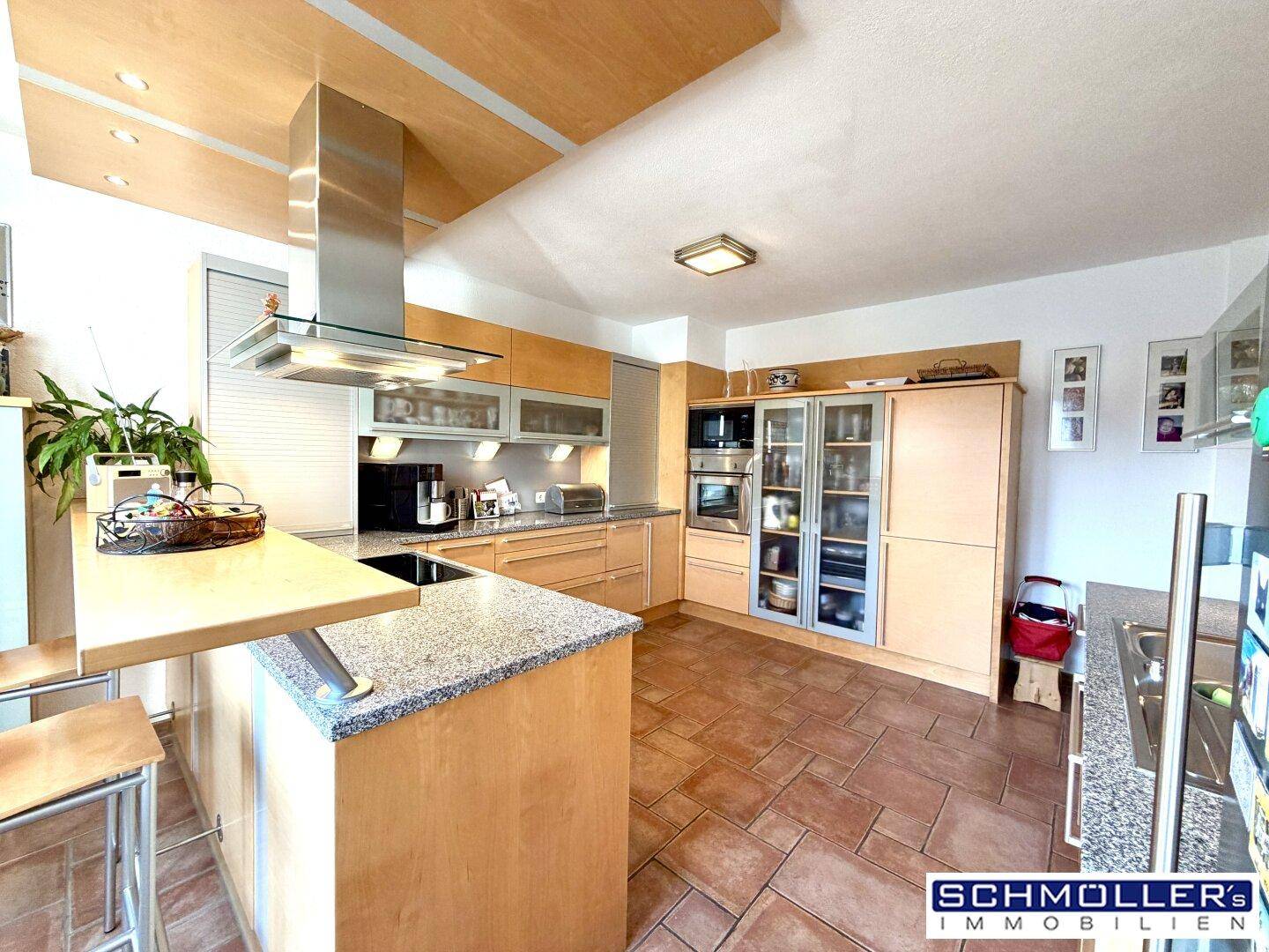 Helle Küche mit Holzschränken, Kücheninsel und modernen Geräten, ideal für gemeinsame Mahlzeiten.