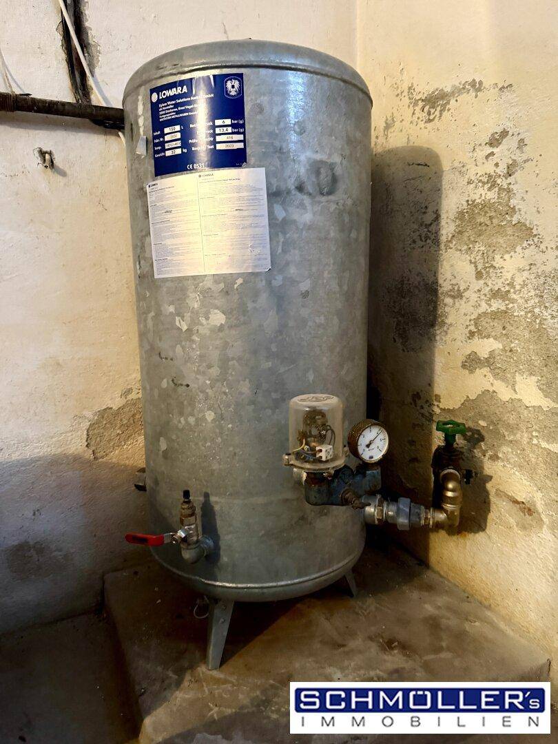 Technikraum mit großem Wassertank und Rohrleitungen, funktional und gut zugänglich.