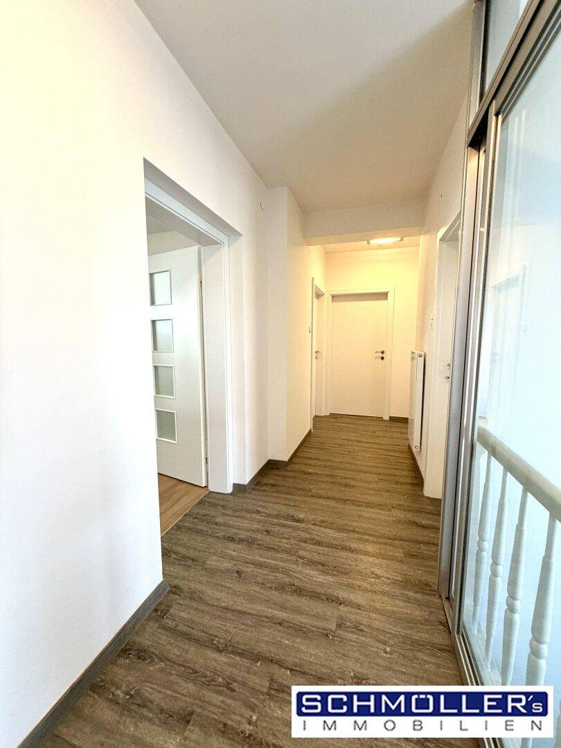 Heller Flur mit modernem Laminatboden und Zugang zu verschiedenen Zimmern.