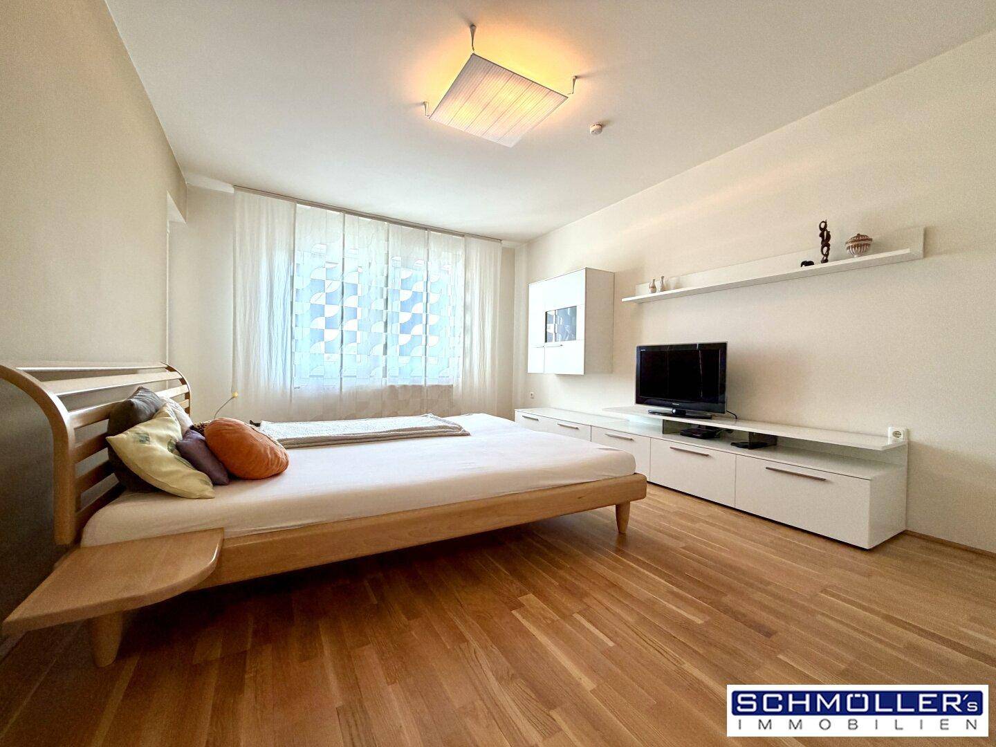 Helles Schlafzimmer mit Holzbett, Parkettboden und weißer Einrichtung, ideal zum Entspannen.