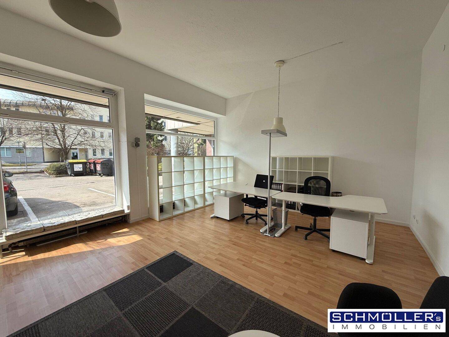 Büroraum mit großen Fenstern, die viel Tageslicht hereinlassen, und modernen Arbeitsplätzen.