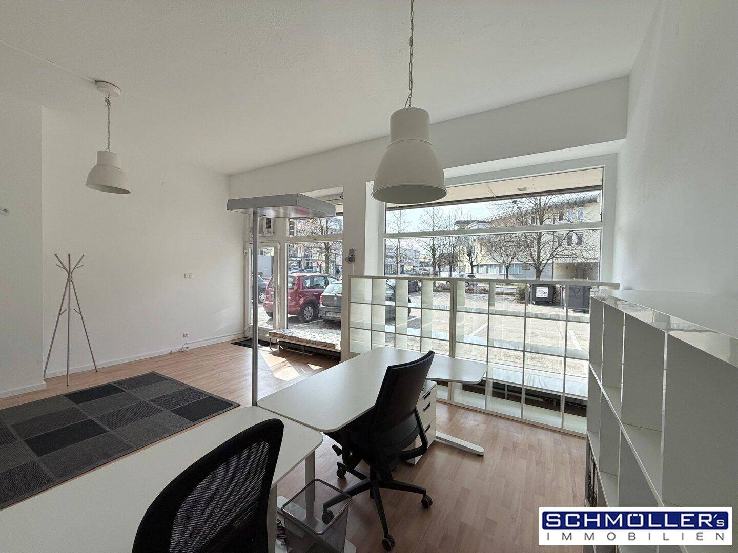 Geräumiges Büro mit hellen Wänden, Holzboden und großen Fenstern, die den Blick nach draußen ermöglichen.