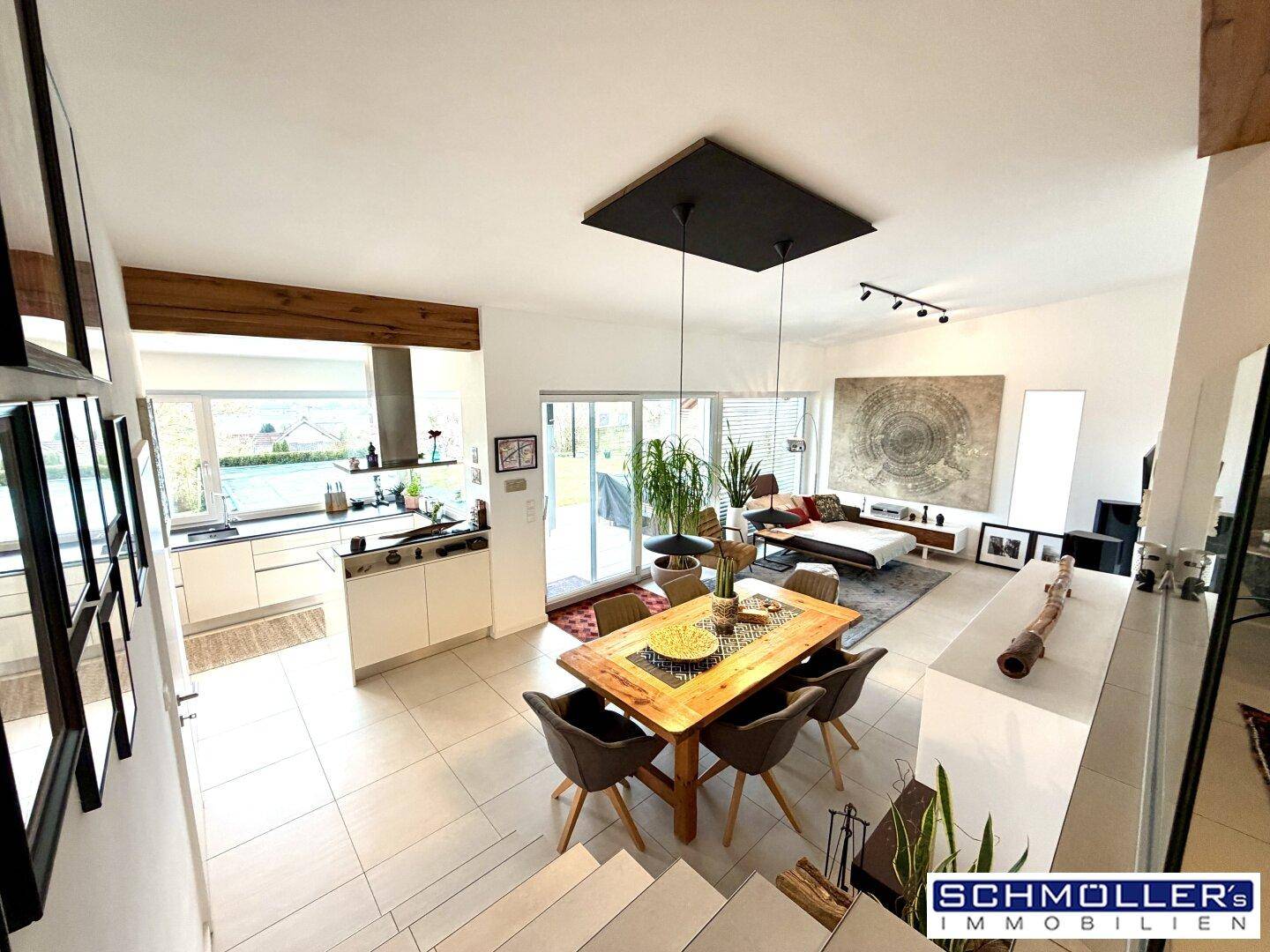 Geräumiger Wohn-Essbereich mit offener Küche, großen Fenstern und Zugang zur Terrasse.