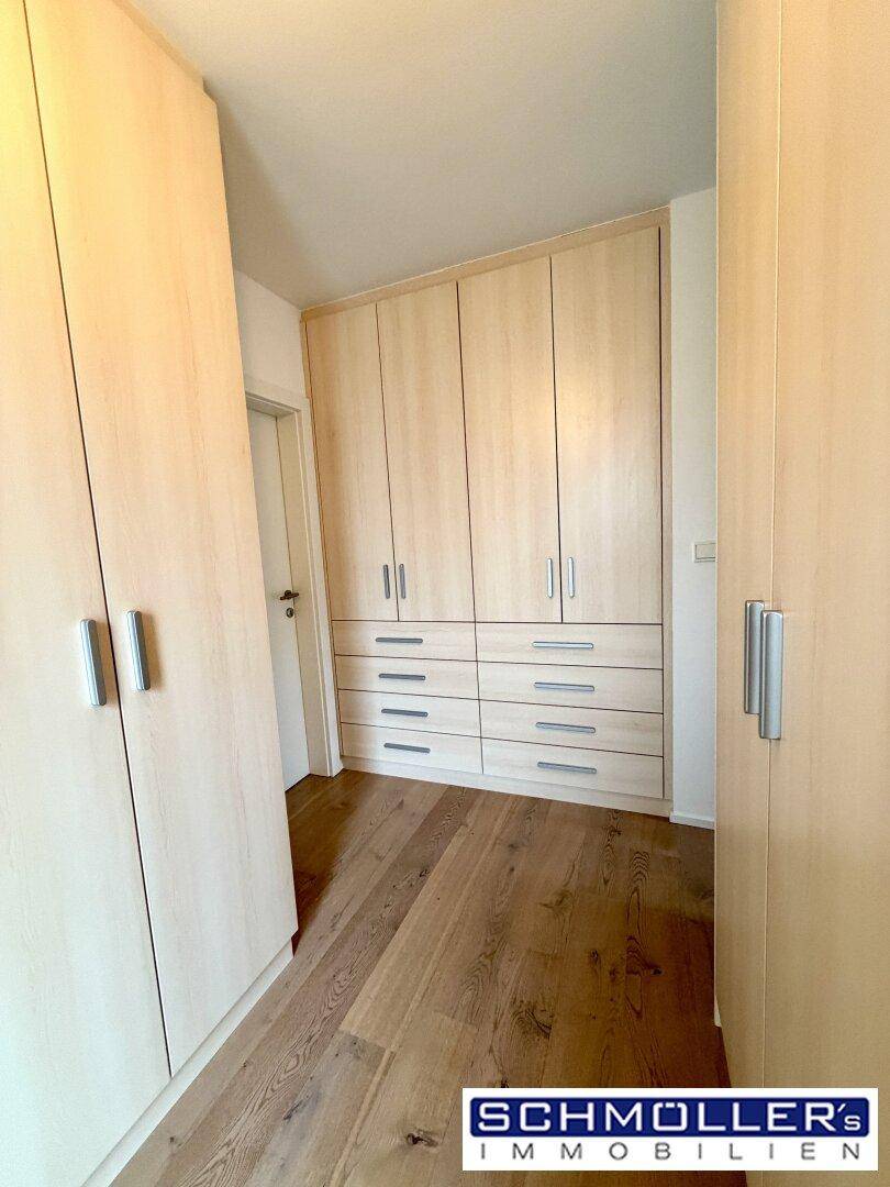 Geräumiger Ankleidebereich mit vielen Einbauschränken und hellem Holzfußboden.