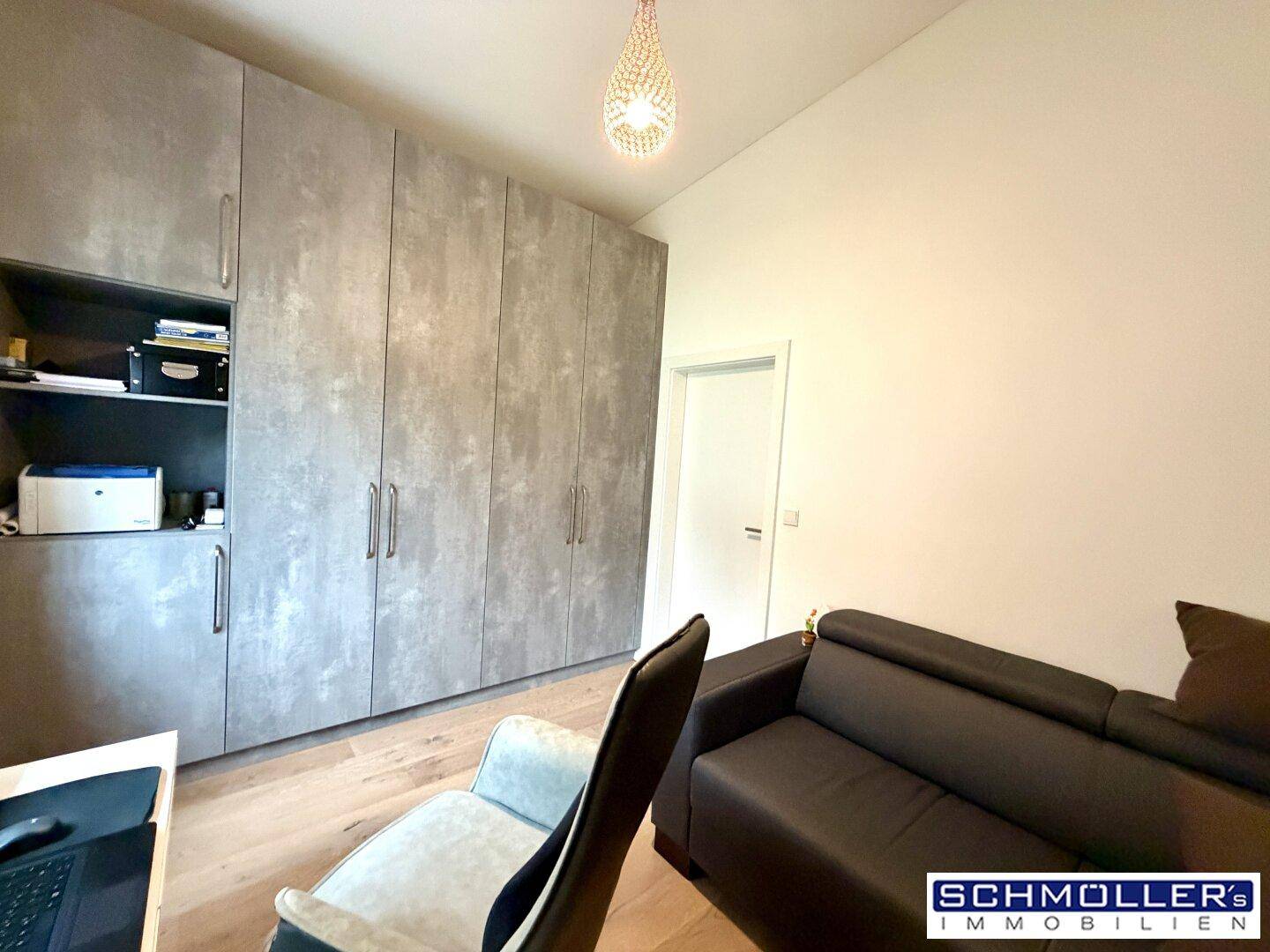 Arbeitszimmer mit großen Einbauschränken und einem bequemen Sofa.