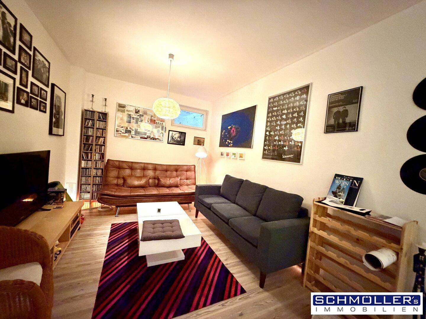 Gemütliches Wohnzimmer mit bequemen Sofas, Holzboden und vielen persönlichen Dekorationen.