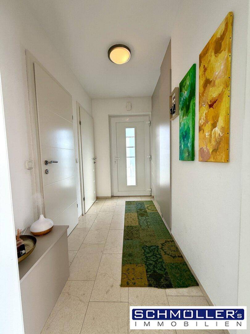 Heller Eingangsbereich mit Fliesenboden und farbenfrohen Kunstwerken an der Wand.