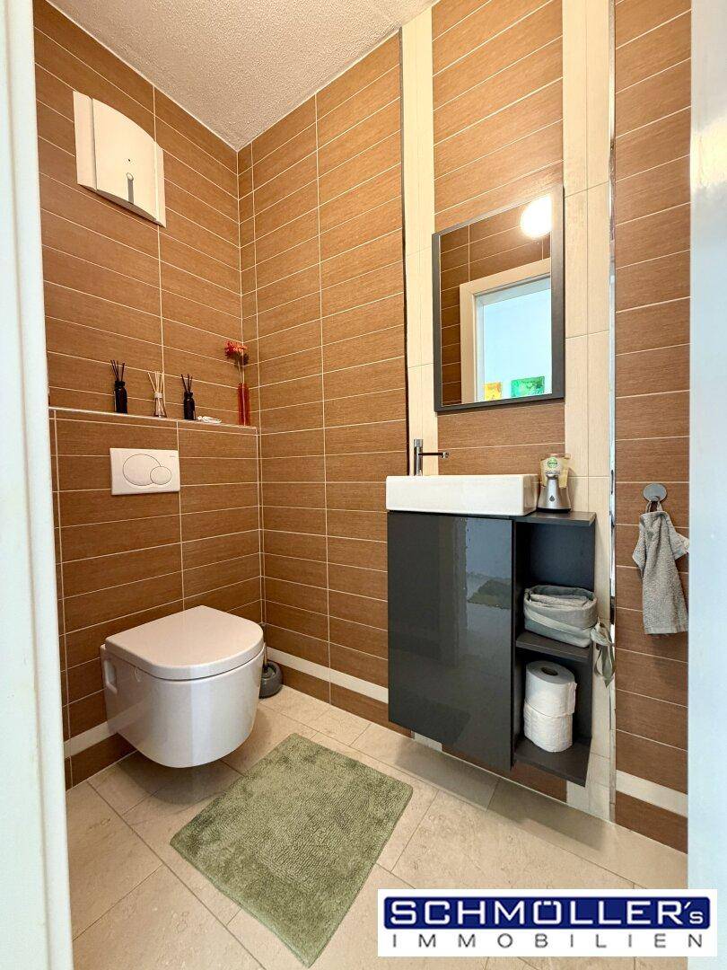 Modernes Gäste-WC mit braunen Wandfliesen, wandhängendem WC und stilvollem Waschtisch.