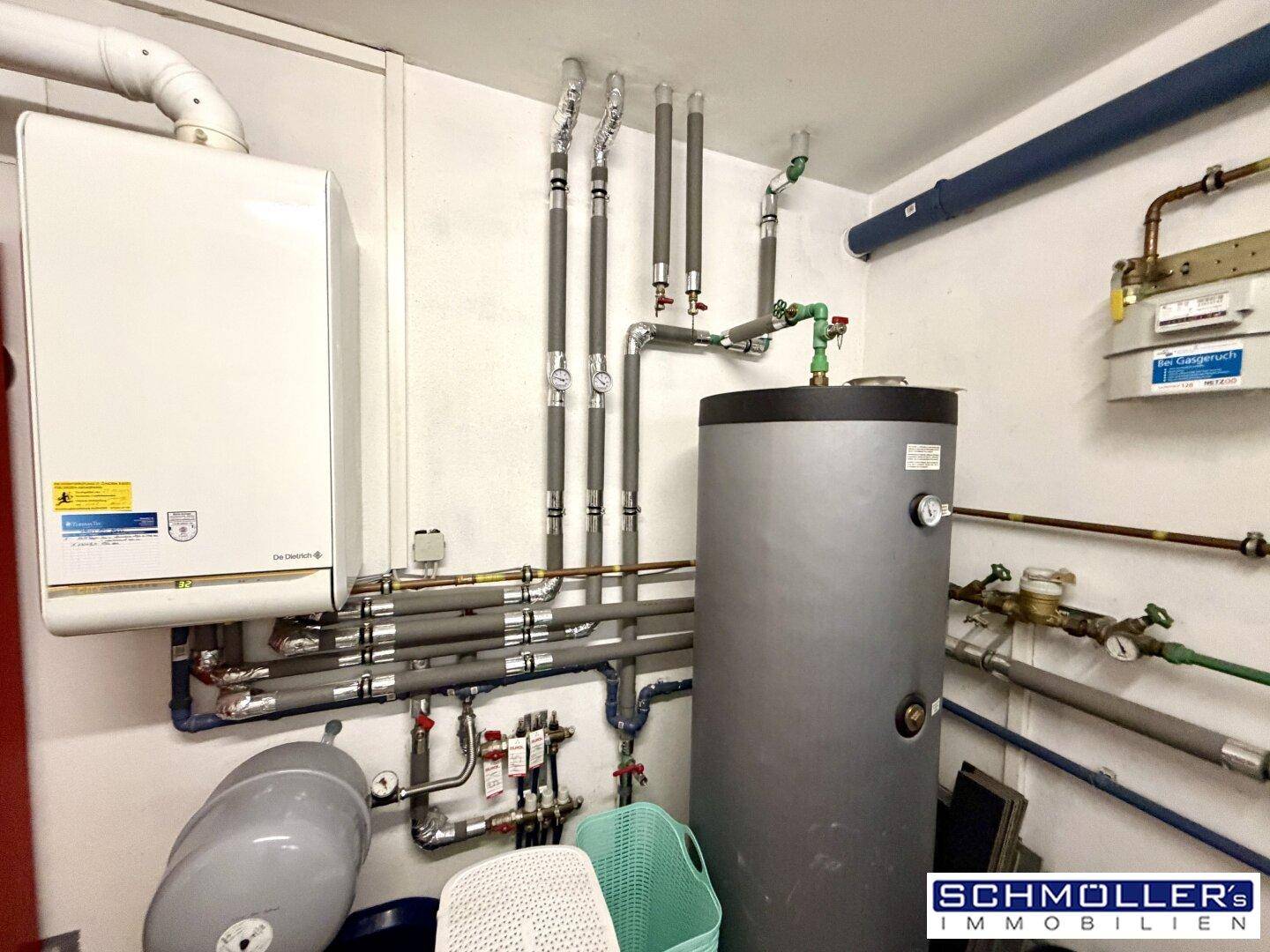 Heizungsraum mit Gastherme, Warmwasserspeicher und sichtbaren Rohrleitungen.