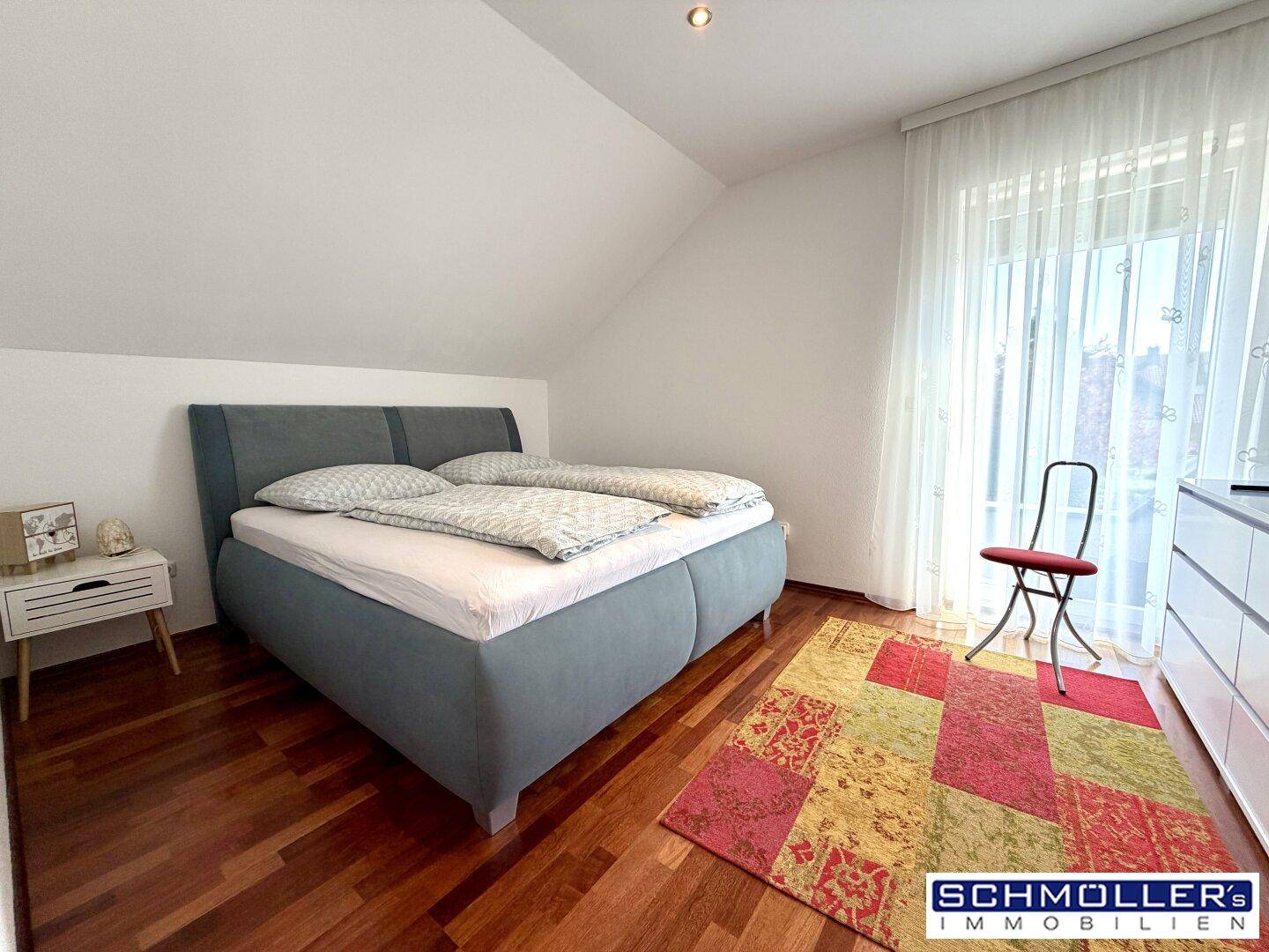 Gemütliches Schlafzimmer im Dachgeschoss mit Holzboden, Doppelbett und schrägen Wänden.