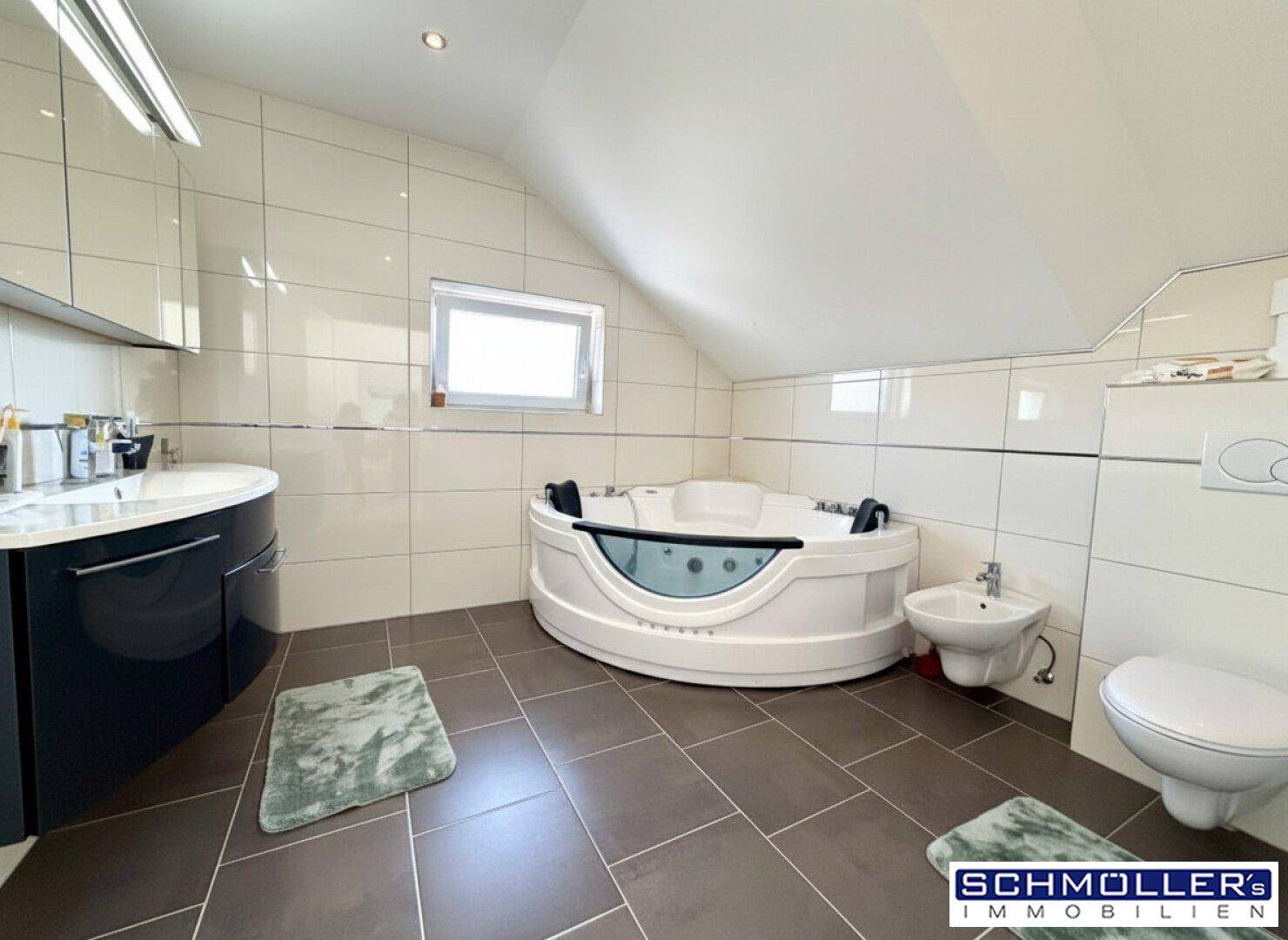 Geräumiges Badezimmer im Dachgeschoss mit Whirlpool-Badewanne, Bidet und Fenster.