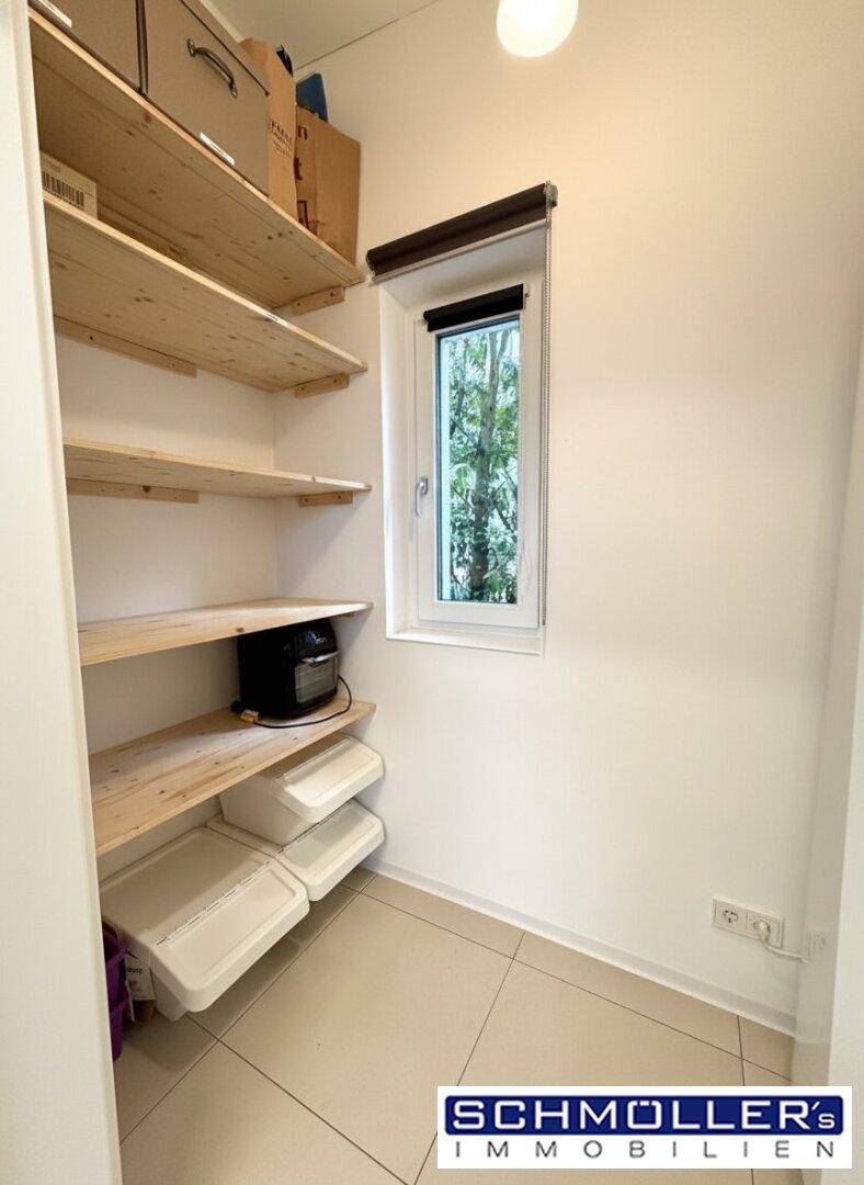 Praktische Speisekammer mit Holzregalen und einem kleinen Fenster für Belüftung.