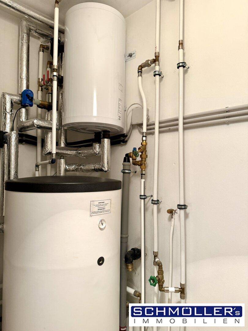 Technikraum mit zwei Warmwasserspeichern und sichtbaren Rohrleitungen.