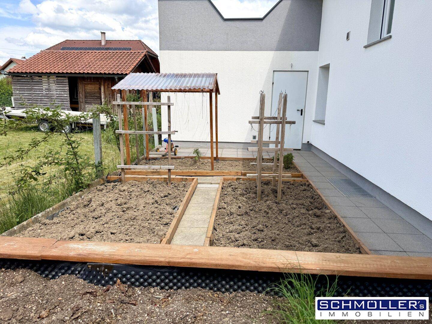 Kleiner Gemüsegarten mit Hochbeeten neben dem modernen Neubau, ideal für den Eigenanbau.