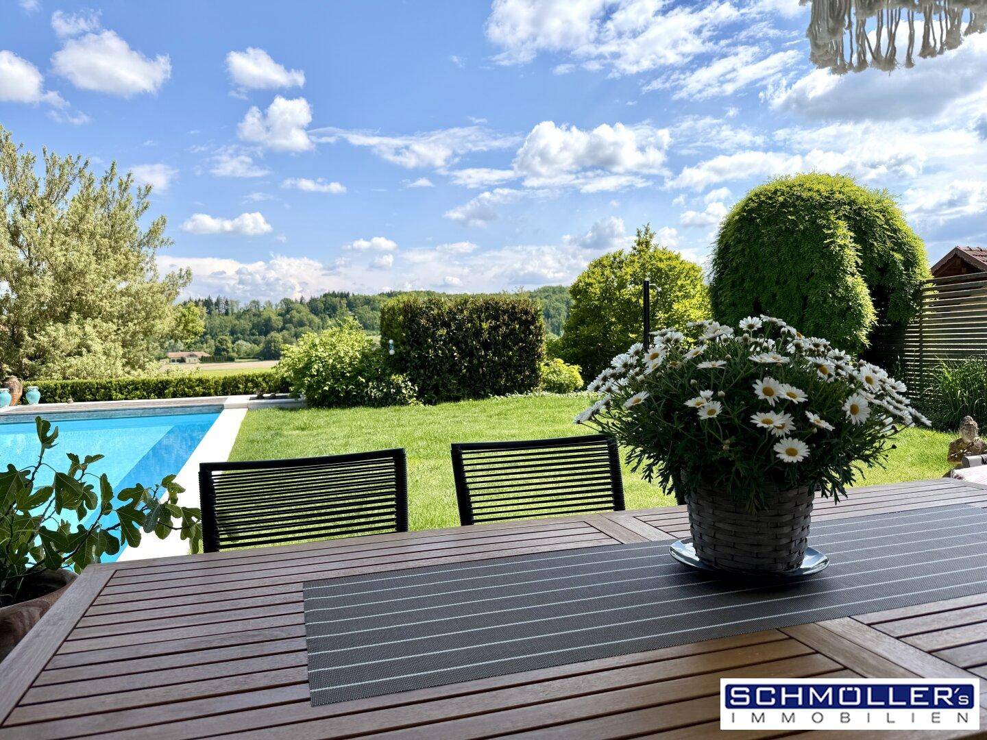 Terrasse mit Gartenmöbeln und Blick auf den Swimmingpool sowie die umliegende Natur.