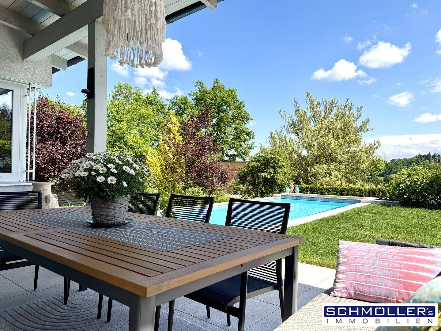 Gemütliche Terrasse mit Esstisch und Blick auf den Pool sowie die grüne Landschaft.