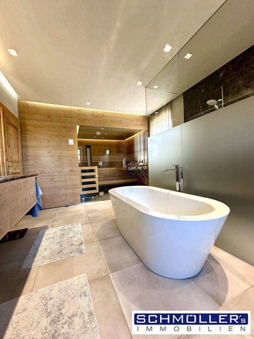Luxuriöses Badezimmer mit freistehender Badewanne, Sauna und modernen Fliesen.