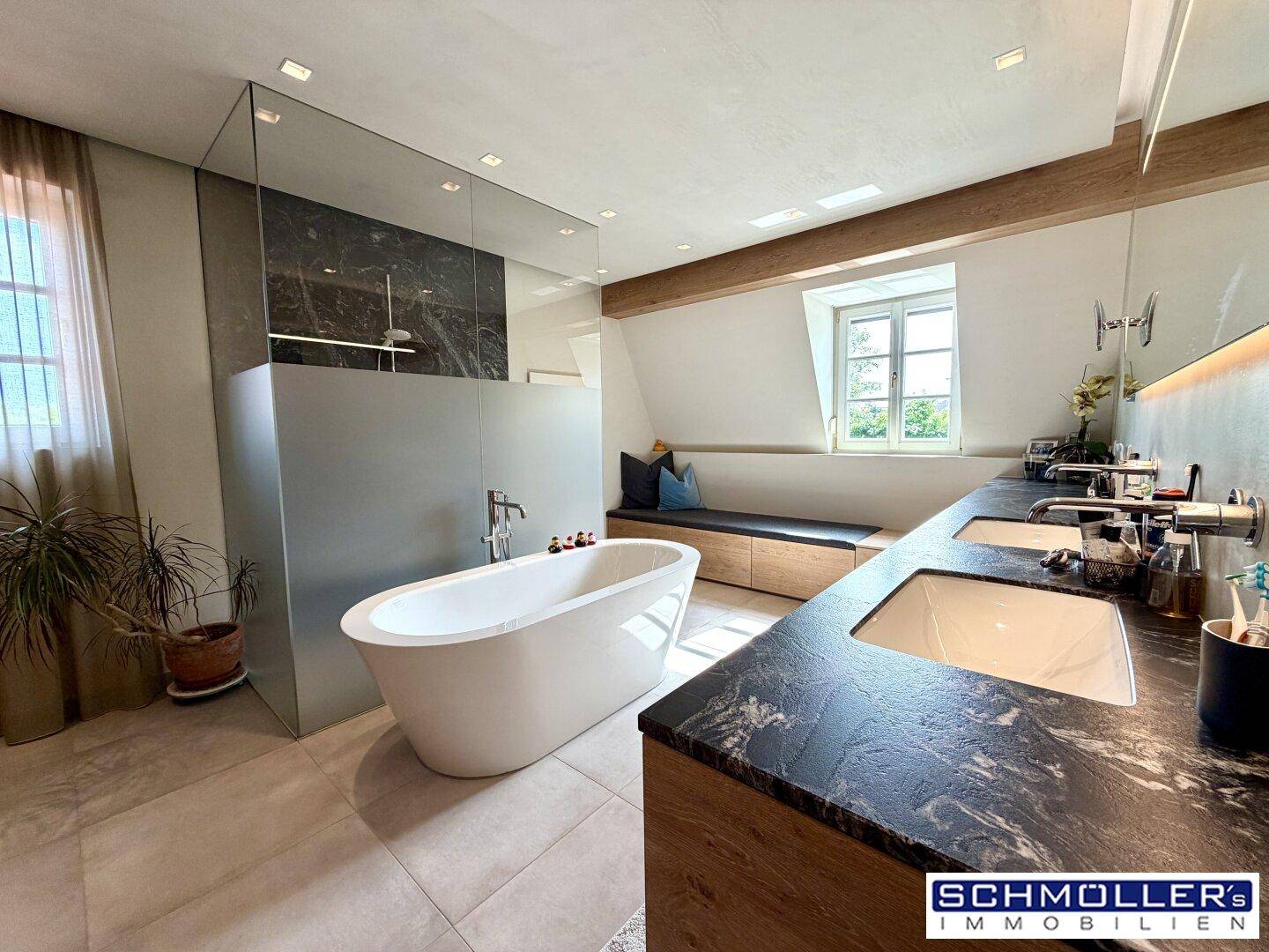 Modernes Badezimmer mit freistehender Badewanne, Doppelwaschbecken und Dachfenster.