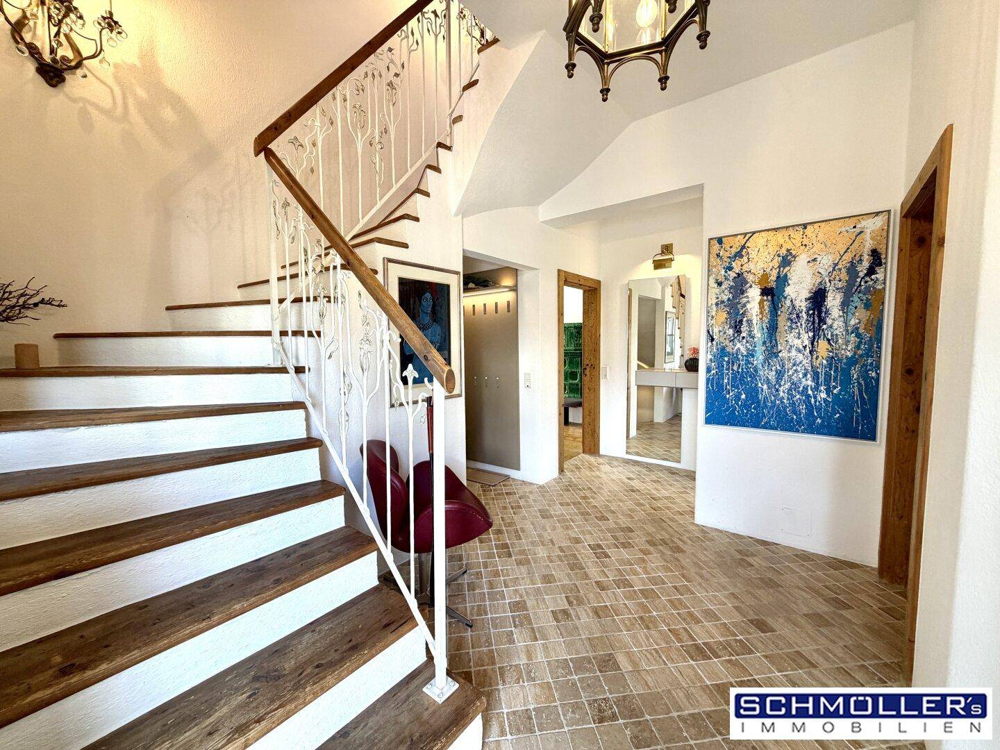 Elegantes Treppenhaus mit Holzstufen, schmiedeeisernem Geländer und Fliesenboden.