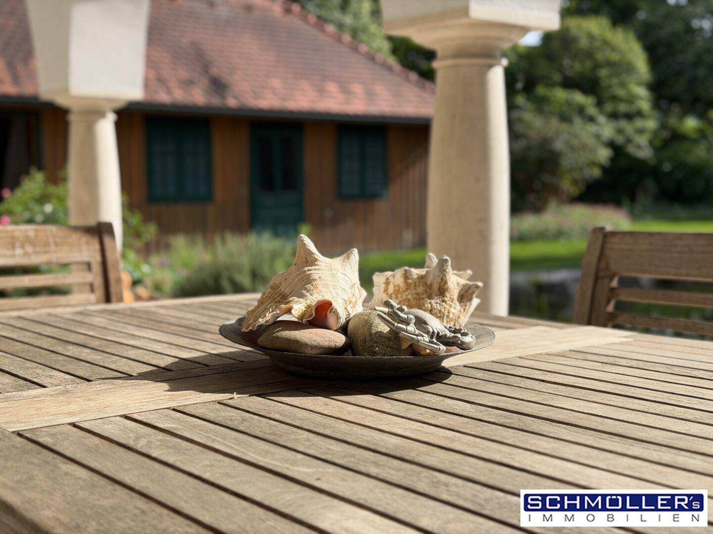 Sonnige Terrasse mit Holztisch und dekorativen Muscheln, ideal für entspannte Stunden im Freien.