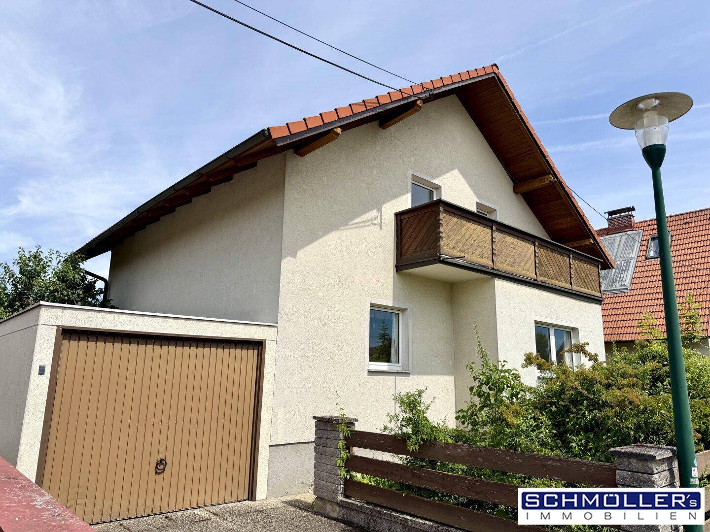 Seitenansicht des Einfamilienhauses mit integrierter Garage und braunem Holztor.