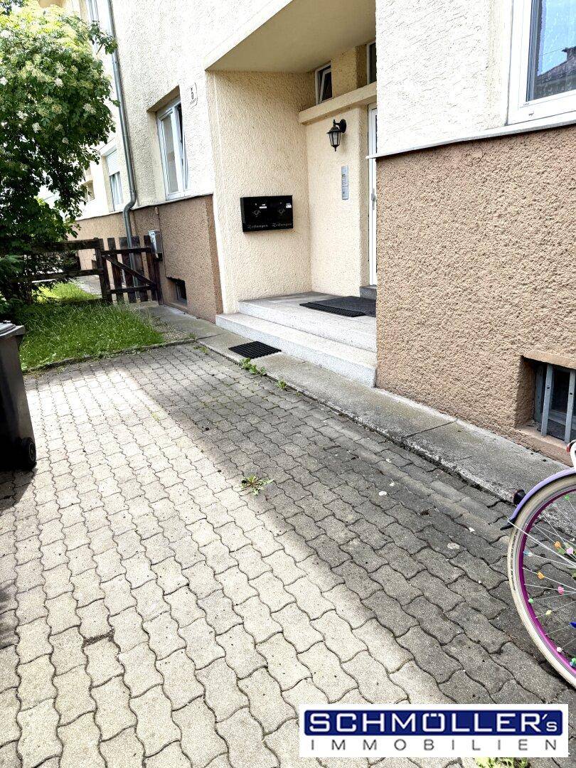 Gepflasterter Eingangsbereich eines Reihenhauses mit Stufen und einer Fahrrad im Vordergrund.