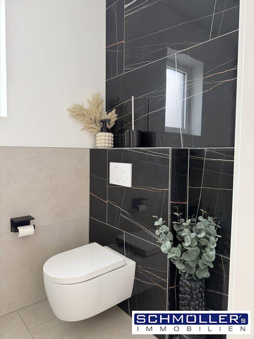 Wandhängendes WC mit eleganten schwarzen Marmorfliesen und modernem Design.