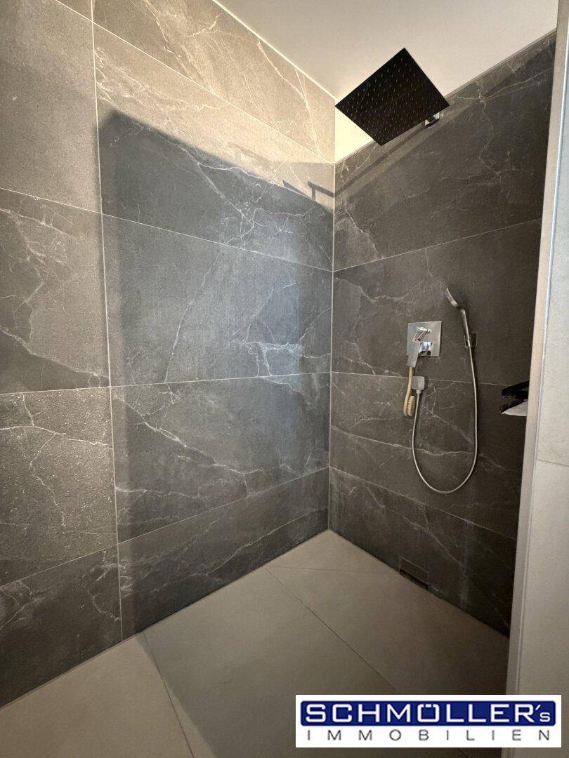Geräumige begehbare Dusche mit Regenduschkopf und eleganten grauen Marmorfliesen.