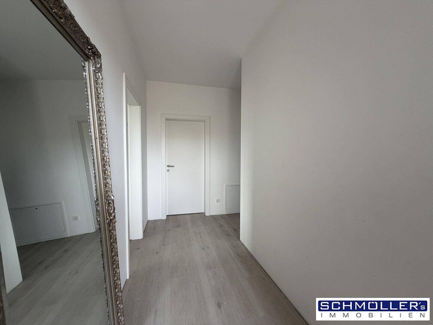 Heller Flur mit großem, antik anmutendem Spiegel und hellem Laminatboden.