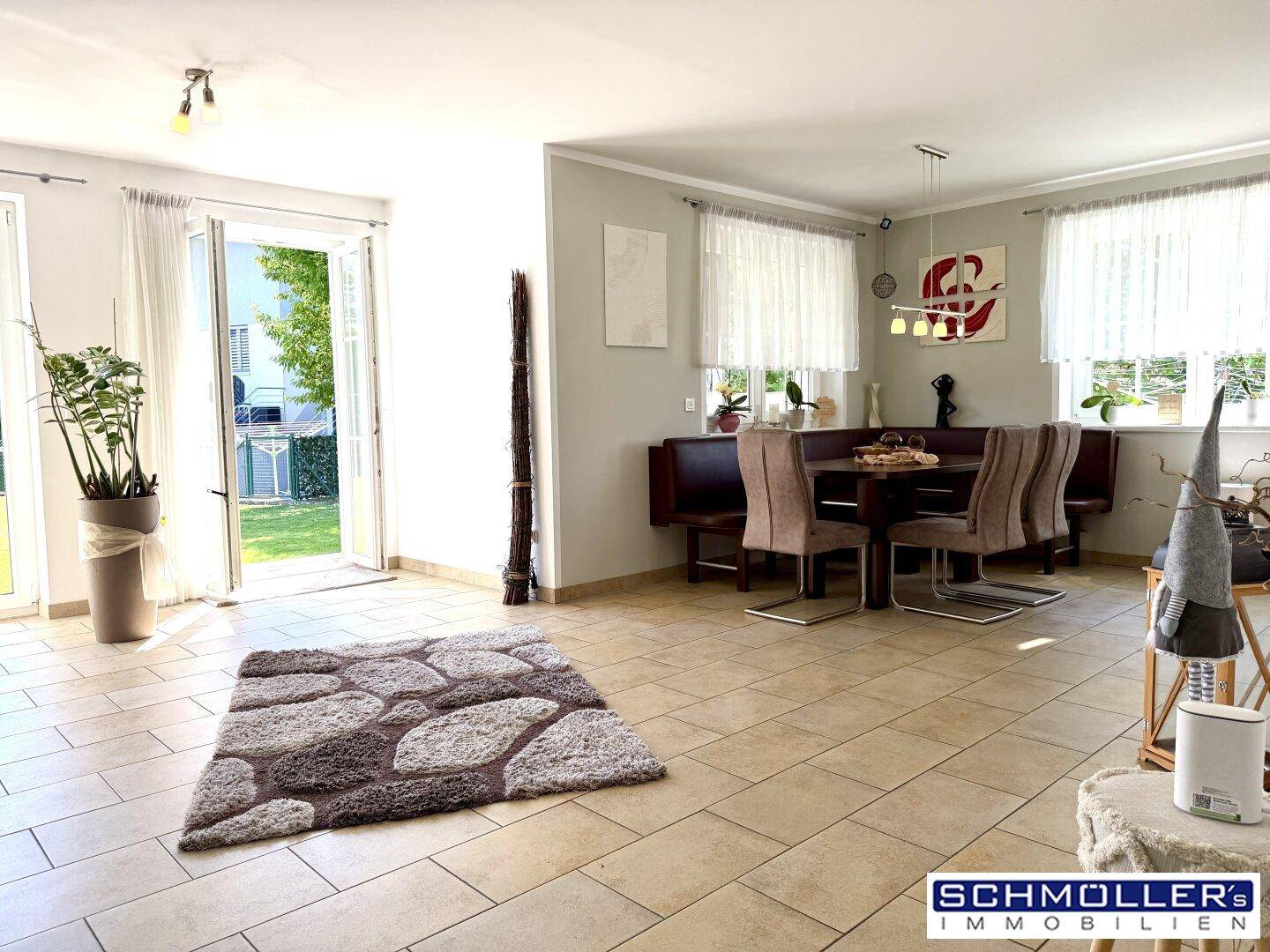 Heller Wohnbereich mit Fliesenboden, Zugang zum Garten und einem gemütlichen Essbereich.